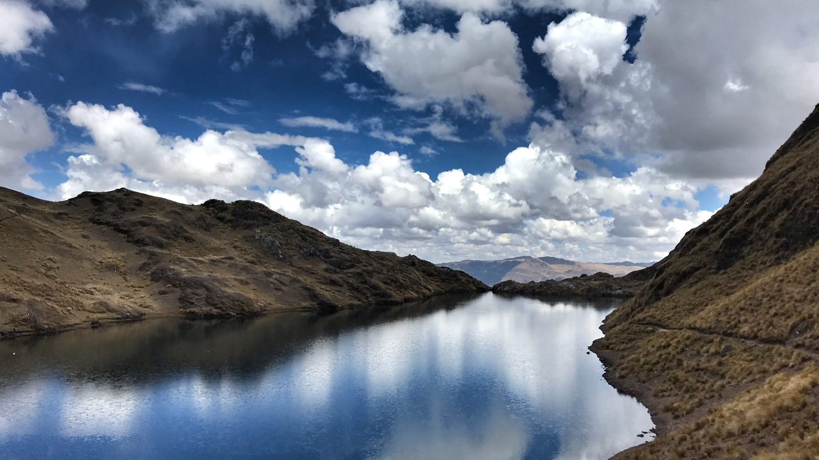 Cloud and blue sky reflected in the flat surface of a high mountain lake