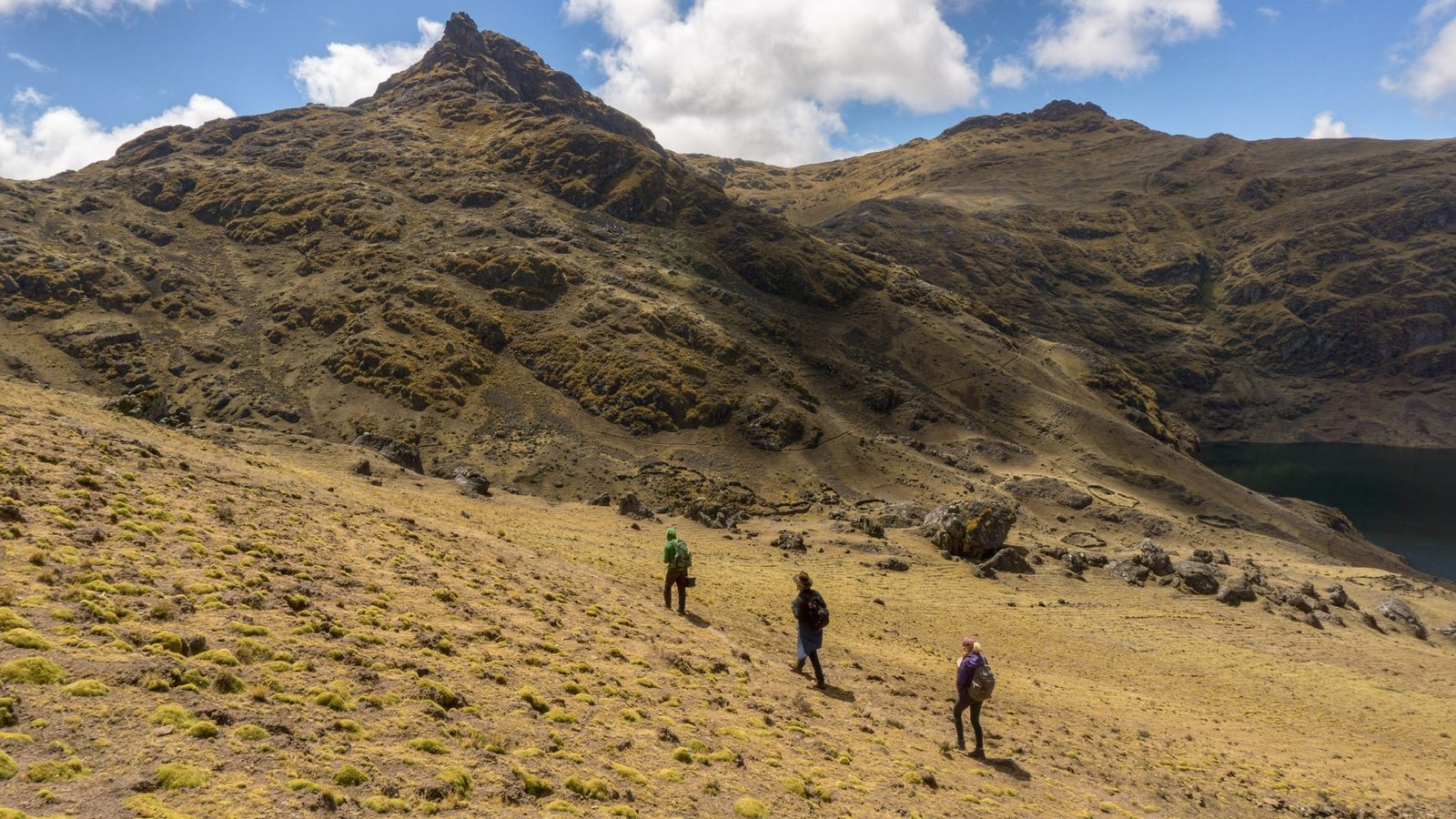 The group strung out along a trail climbing a bare golden ridge on a ceremony day